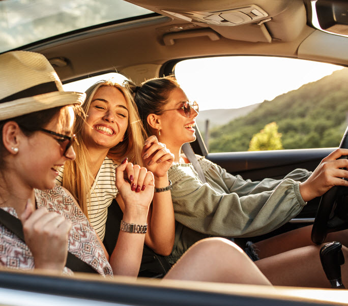 A woman hanging out of the car window smiling and laughing