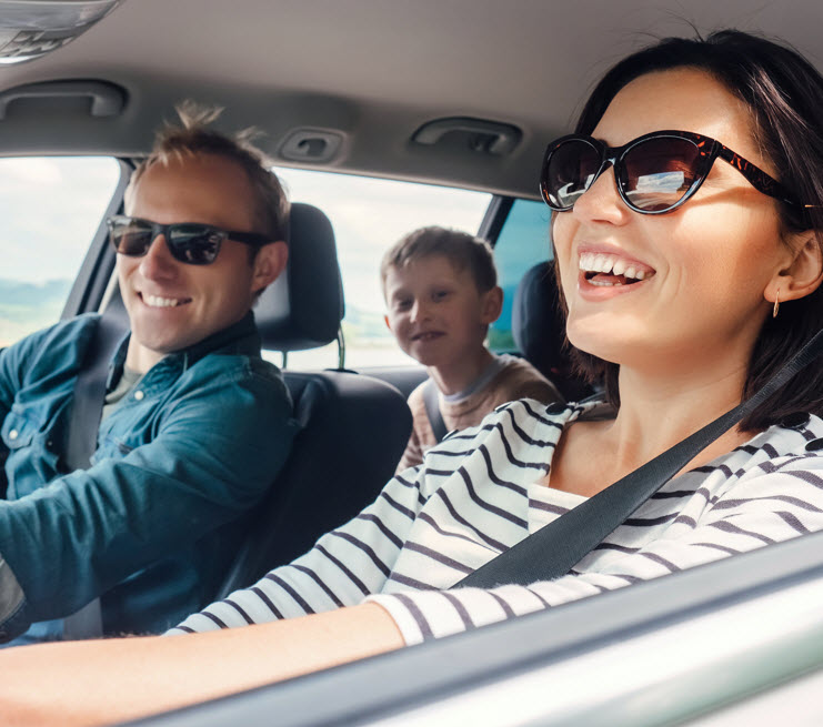 Man with glasses in the drivers seat of a car smiling