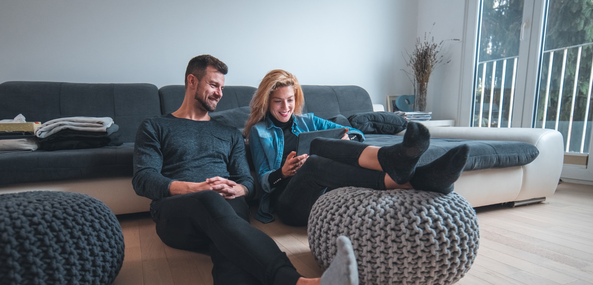 Couple sitting in living room while looking at tablet